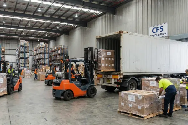 LCL cargo consolidation at a container freight station with forklifts loading palletised shipments into a shared shipping container
